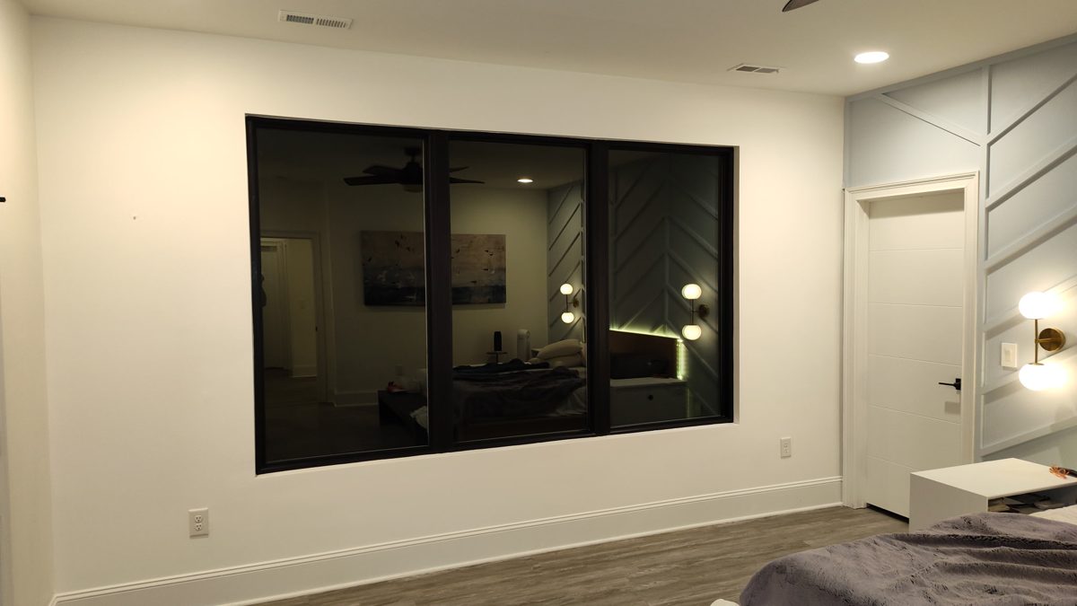Large black-frame picture window in a bedroom