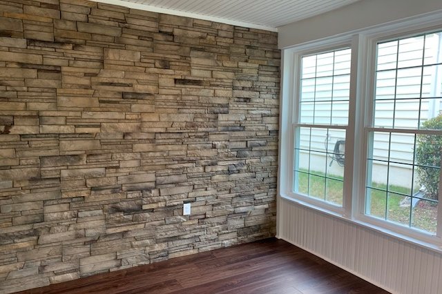 Room with white gridded windows beside a stone wall