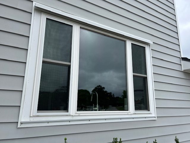 Picture window flanked by two operable windows on gray siding