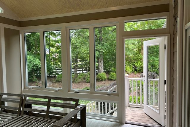 Room with a wall of windows and an open door to the backyard