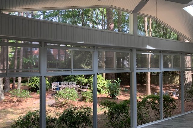 Inside a screened porch looking out at a wooded backyard
