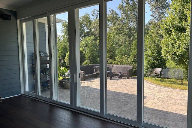 Inside view of a sliding glass wall facing a patio and trees
