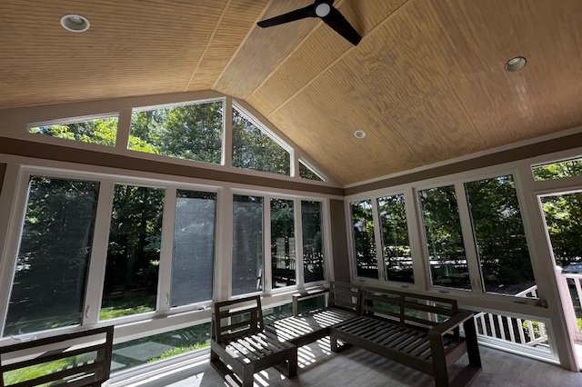 Sunroom interior with a wood ceiling, ceiling fan, and walls of windows