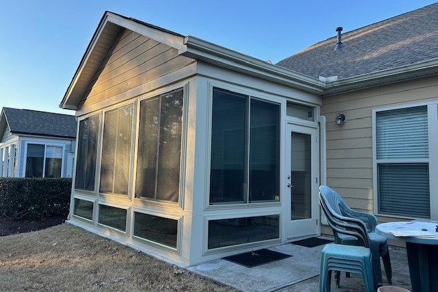 Tan-sided home with a sunroom addition and patio