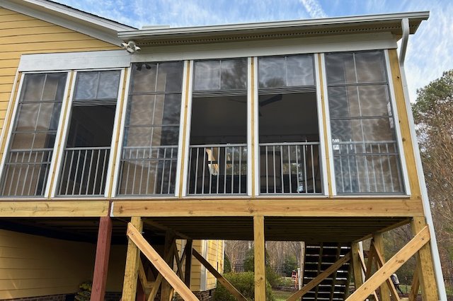 Close view of yellow siding and windows on a raised addition