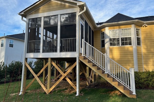 Two-story home with yellow vinyl siding and a raised addition